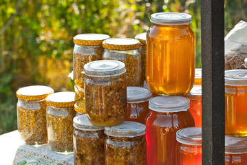 Different types of honey on the table. The colorful jars of honey are sold at the agricultural produce fair.