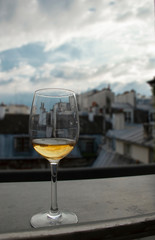 Glass of white wine on window sill with view of Paris roof tops