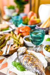 Dining table with different foods, snacks and flowers. Summer lunch in the open air. Seafood and vegetables.  