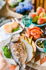 Dining table with different foods, snacks and flowers. Summer lunch in the open air. Seafood and vegetables.  