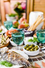 Fried fish on a plate. Dining table with different food and snacks. Seafood and vegetables. Summer lunch in the open air.