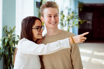 Young female and male students gossiping and bulling on somebudy in corridor of the college. Two...