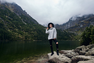 Girl staying on rocks near lake. Tatra mountains landscape in Poland, Zakopane. Mountain landscape in Eastern Europe.