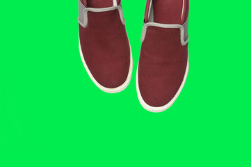 Casual brown sneakers on green background.