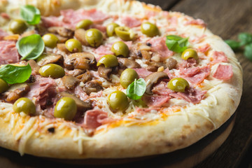 Pizza with prosciutto, olives and fresh basil