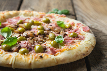 Pizza with prosciutto, olives and fresh basil