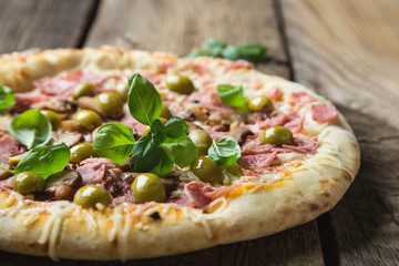 Pizza with prosciutto, olives and fresh basil