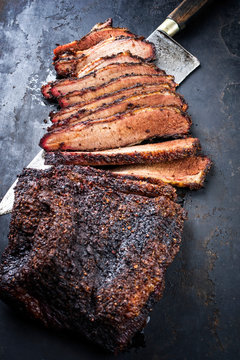 Traditional smoked barbecue wagyu beef brisket offered as closeup with knife on an old rustic board with copy space