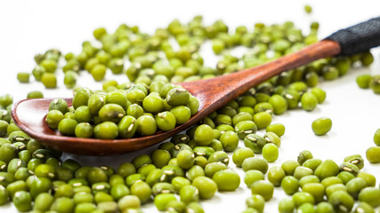 Raw green mung beans in wooden spoon closeup on a white background. Healthy vegetarian food. Food background concept.