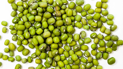 Scattered green grains of Mung Beans on a white background, top view. Healthy vegetarian food. Food background concept.