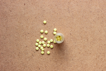 Yellow pills with bottle on green mint background, Healthy and Medicine concept. Yellow tablets. Yellow pills on a brown surface. Yellow tablets on a dark surface
