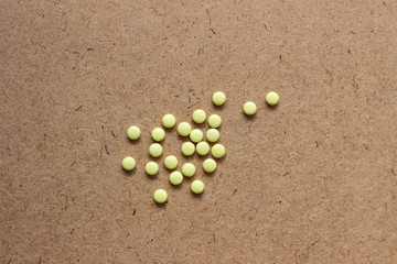 Yellow pills with bottle on green mint background, Healthy and Medicine concept. Yellow tablets. Yellow pills on a brown surface. Yellow tablets on a dark surface