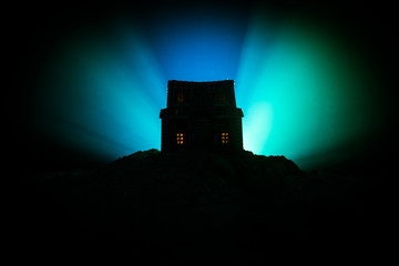 Obraz premium Old house with a Ghost in the forest at night or Abandoned Haunted Horror House in fog. Old mystic building in dead tree forest. Trees at night with moon. Surreal lights.