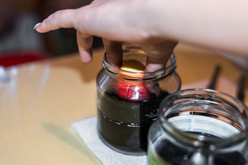 Junge Frau färbt Ostereier Zuhause in der Küche im Gurkenglas und mit verschiedenen Farben, Deutschland