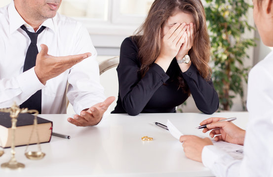 partial view of lawyer and client sitting at table with divorce decree and wedding rings