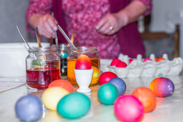 Alte Frau färbt Ostereier Zuhause in der Küche im Gurkenglas und mit verschiedenen Farben, Deutschland