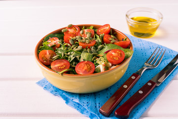 Vegetable salad with tomato, lettuce, pumpkin seeds, in a salad bowl.