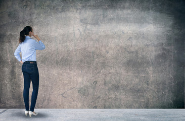 Young woman looking at the wall with space for your text or image. thinking and analysing idea.