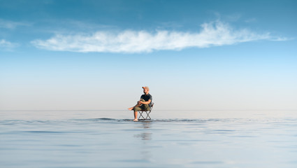 Fototapeta na wymiar A man sits on a chair in the middle of the sea