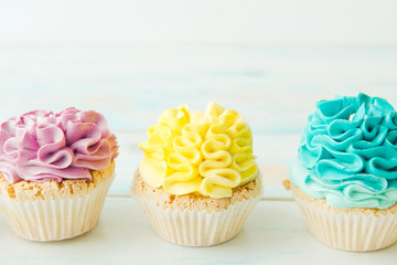 Three colorful cupcakes on a light background. Copy space