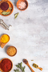 Dried herb and spice food in spoons and bowls on stone as frame, flat lay