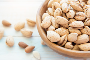 Wooden bowl with shelled almonds on a light table