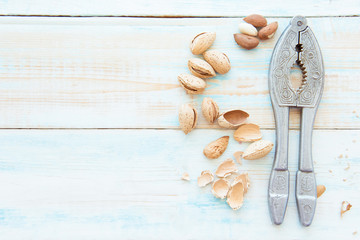 Almonds in husk and Nutcracker on light wooden background