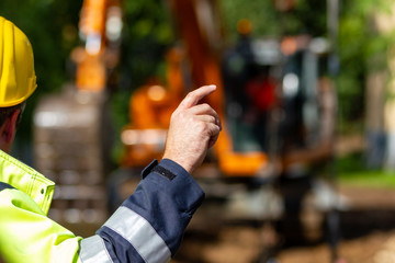 Vorarbeiter dirigiert Bagger - Helm gelb