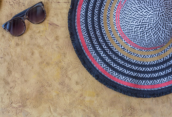 Flat lay of summer accessories and shoes on yellow sand background. Summer outfit concept.