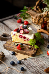 Homemade delicious slice of raspberry biscuit cake with white cream, strawberries, blueberries