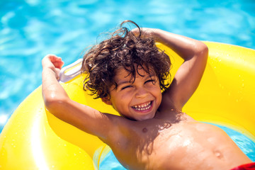 Kid boy swims with inflatable circle in the pool. Children, summer and holiday concept