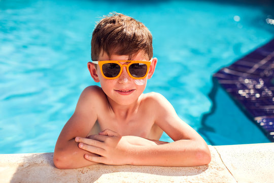 Kid boy with sun protection cream on his skin in the pool. Children, summer, holiday and healthcare concept