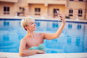 Woman spends time and has relax on the pool with phone. People, summer and holiday concept