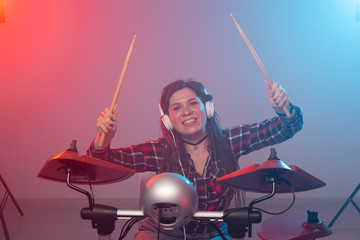 Electronic drum set, music and hobby concept - young woman drummer playing in headphones