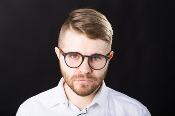 Portrait of bearded serious handsome man looking at camera isolated over black background