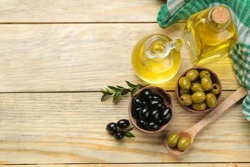 Foto op Plexiglas Green and black olives in a wooden bowl with leaves and olive oil on a natural wooden table. top view. © MK studio