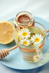 Chamomile flowers and chamomile tea. Chamomile tea in glass teacup with flowers, honey and lemon, top view, prevention of seasona flu colds