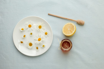 Chamomile flowers and chamomile tea. Chamomile tea in glass teacup with flowers, honey and lemon, top view, prevention of seasona flu colds