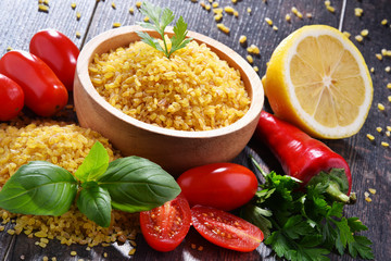 Bowl of uncooked bulgur on wooden table