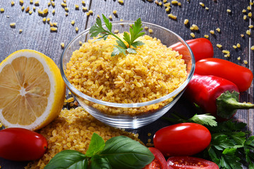 Bowl of uncooked bulgur on wooden table