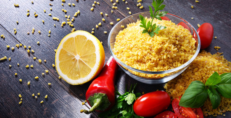 Bowl of uncooked bulgur on wooden table