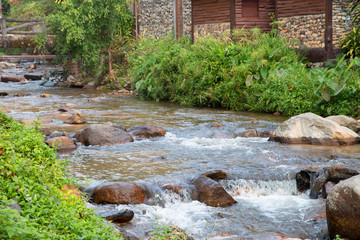 calm mountain water stream flowing with wooden house.