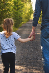 Fototapeta na wymiar Father and daughter walking in the park holding hands. We will love and take care of you forever concept.