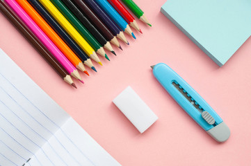 Notebook and colored pencils on a pink  background
