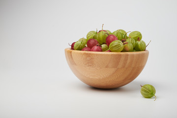 Gooseberries fruits on white background. Bowls with gooseberries isolated on white background. Red and green gooseberries in a bowl with copy space for text. Ripe gooseberry close-up.  K