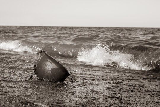 Black and White photo of military helmet on beach in the water.  