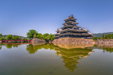 Fototapeta premium Matsumoto - May 25, 2019: The castle of Matsumoto and the red bridge leading to it, Japan
