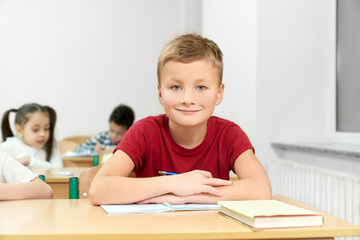 Male student sitting at desk with folded arms during lesson