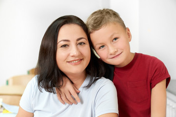 Front view of happy mother posing with little son