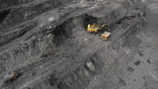 Big yellow heavy truck in open cast mine mining of coal the overall plan. Open pit anthracite mining, mining truck at work working in quarry. Dumpers quarrying industry mining work of machinery trucks